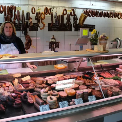 a woman behind a counter of meats